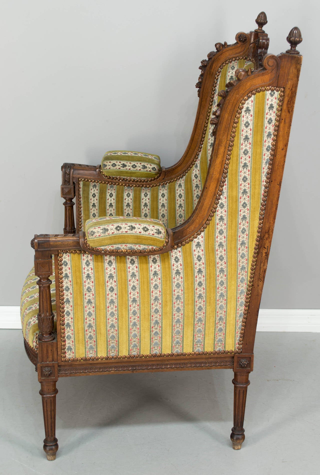 19th c. French Louis XVI style bergere or wingback armchair, c.1860-1880 Very sturdy and comfortable with great carved details: garlands of roses at the top, scrolls with rosettes and acorn finials. Original upholstery. As always, more photos