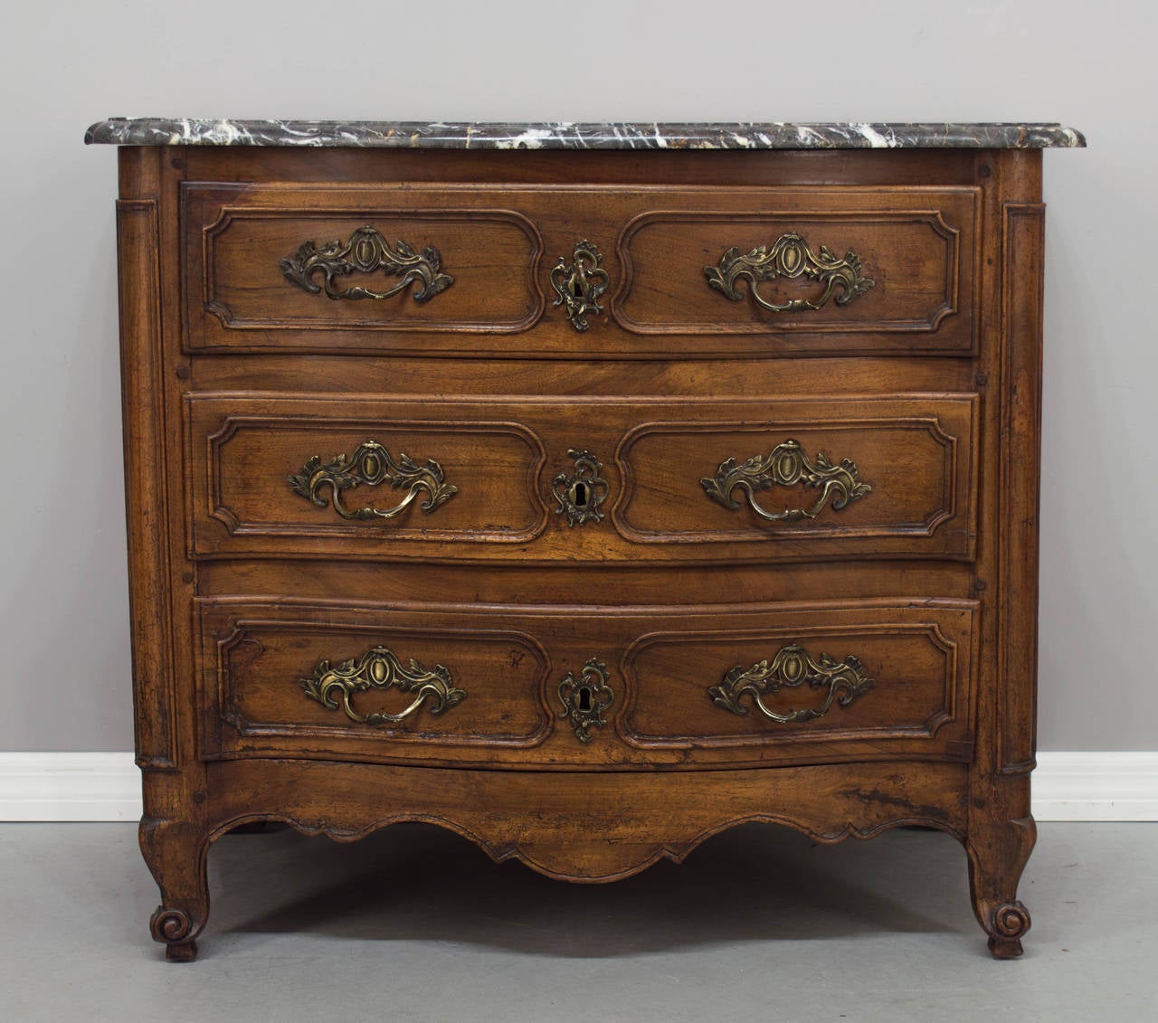 18th century French Louis XV period commode with serpentine front and curved sides, probably from the Burgundy region. Made of walnut with three dovetailed drawers. Bronze hardware is old and of the period, but not original to the piece. Working