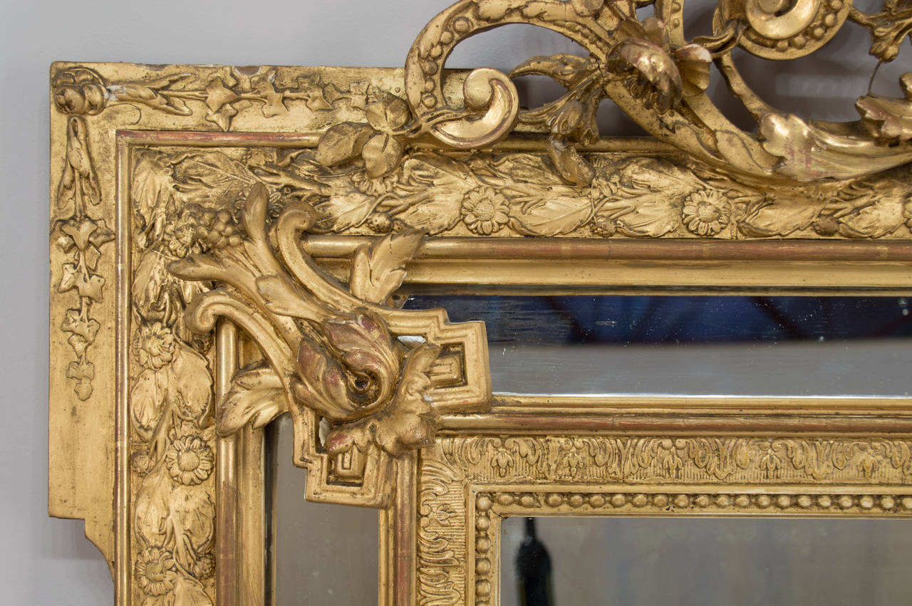 A 19th c. Napoleon III mirror with elaborately carved and gilded gesso frame.  Decoration includes a central crest carved in high relief flanked by curving acanthus leaves and flowering branches. Perimeter of frame is carved in low relief in a