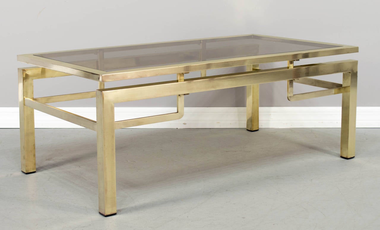 French coffee table designed by Guy Lefevre for Maison Jansen. Made of polished brass with the original smoke glass top. Fine quality construction and timeless design.