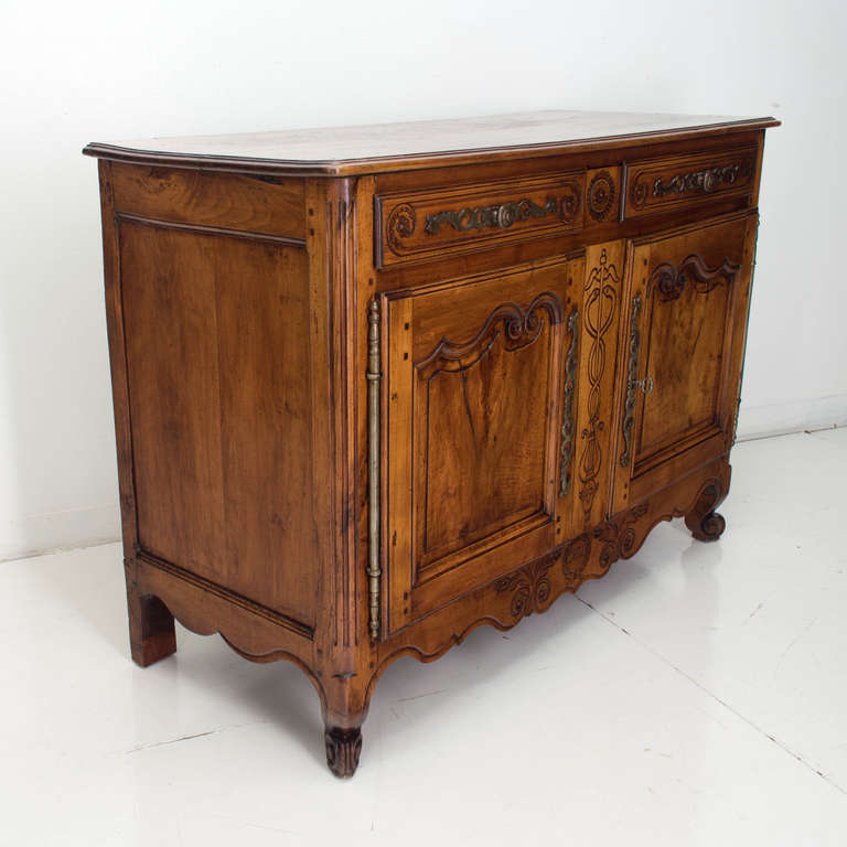A buffet from the Loire Valley made of solid walnut, with two raised panel doors above an apron with carved frieze and two drawers flanking a secret drawer. 
This buffet is dated 1831 and was made for a doctor or pharmacist. One shelf on the
