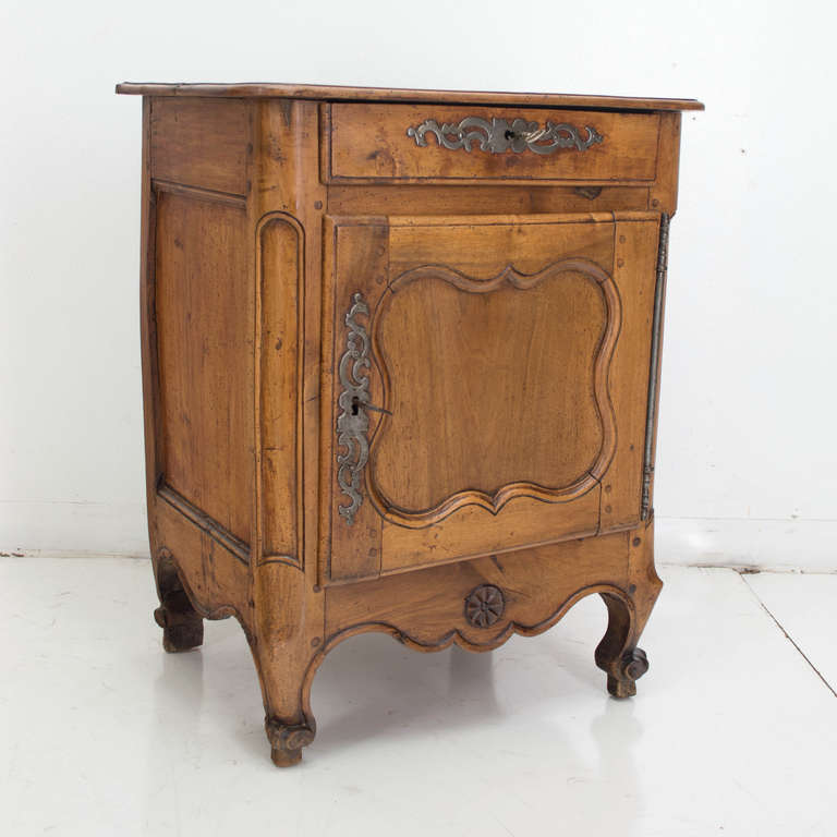 A rare original confiturier (a single door buffet), made of pear wood with original hardware, having a carved apron with two front scroll feet and two carved feet on the back, a panel shaped door below of a drawer. Locks are original and in working