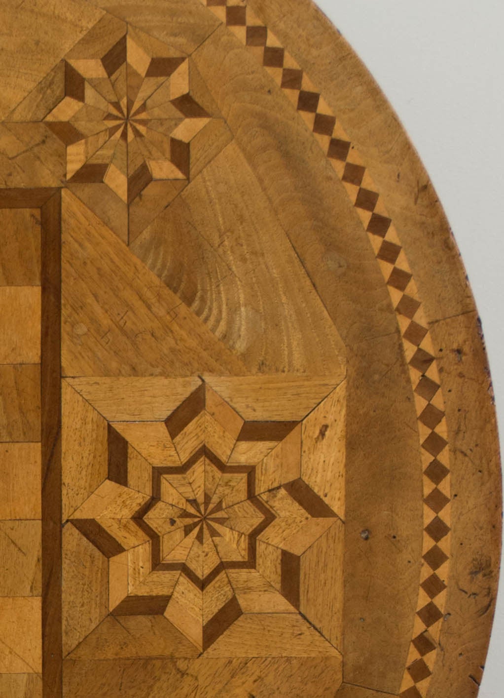 19th century tilt-top game table made of walnut, with various wood veneers used for the marquetry checkerboard and star patterns. The turned base is solid walnut with three hand-carved feet held in place by wooden screws (see detail photo). This is
