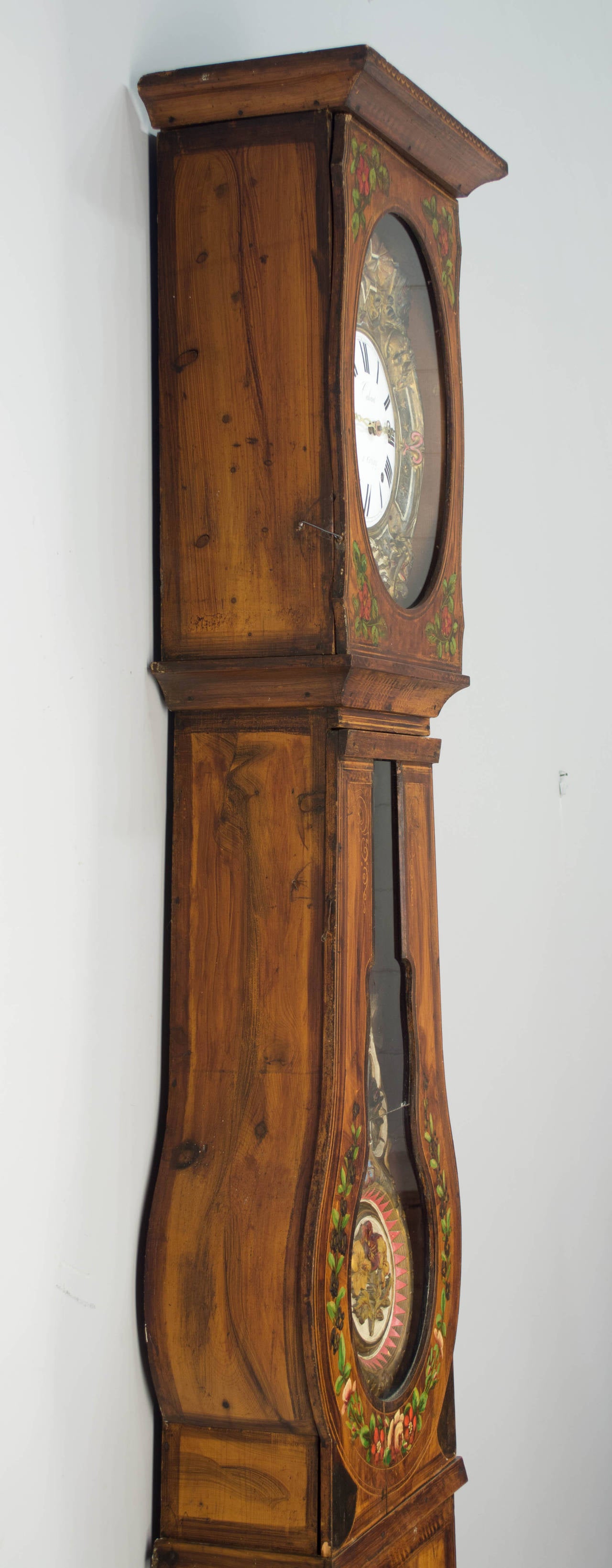 A comtoise or grandfather clock with polychrome painted pine case and brass embossment. Seven day clock, in working condition and professionally cleaned, strikes on the hour, two minutes after the hour and once on the half. This clock was sold by