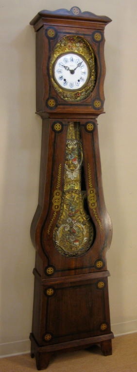 A seven day comtoise with original brass embossed pendulum and face. Original polychrome paint. Movement has been cleaned and is in working condition. Replaced bottom glass. Case is made of pine and has no restoration.<br />
<br />
Chimes on the