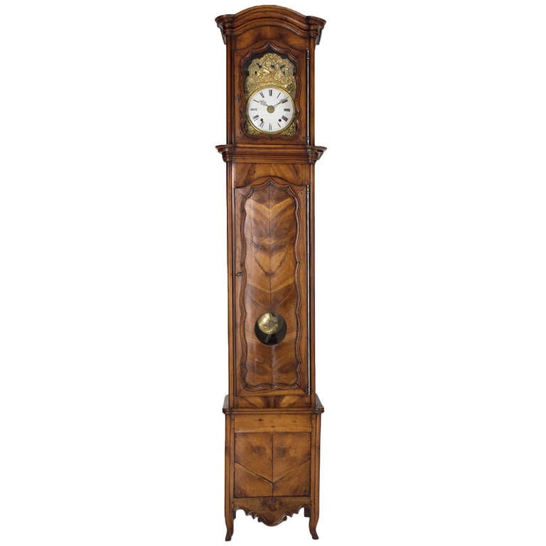 A tall case clock from the Normandy Province of France, made of cherry and chestnut in two parts. The case is pegged constructed with a chapeau de gendarme crown, veneer of cherry on the panel of the large door and the bottom part. Morbier movement,