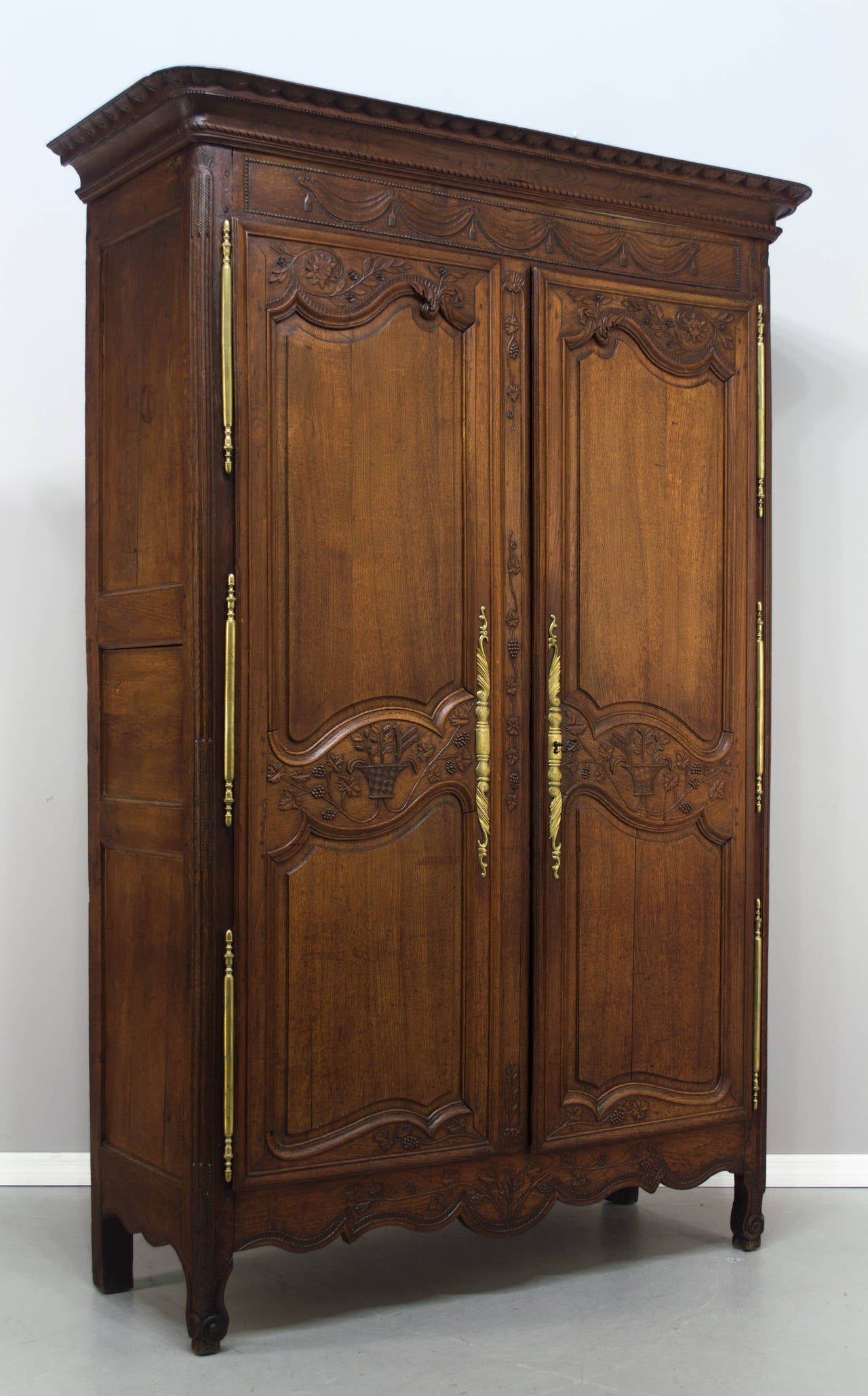 18th c. French Country armoire from Normandy, large in scale and made of oak with nice hand carvings including baskets and trailing grape vines on door panels, drapes and tassels at the top, and herringbone pattern on the corners between the hinges.