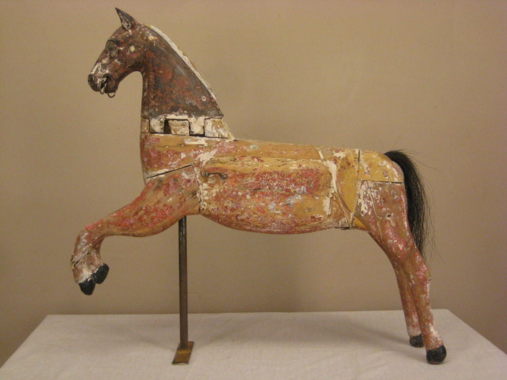 This delicate horse was probably created foe a child's carousel. The juxtaposition of the finely worked and detail cast iron head and the simplicity of the carved and pieced wooden body, make this a  particularly captivation example of Provencal