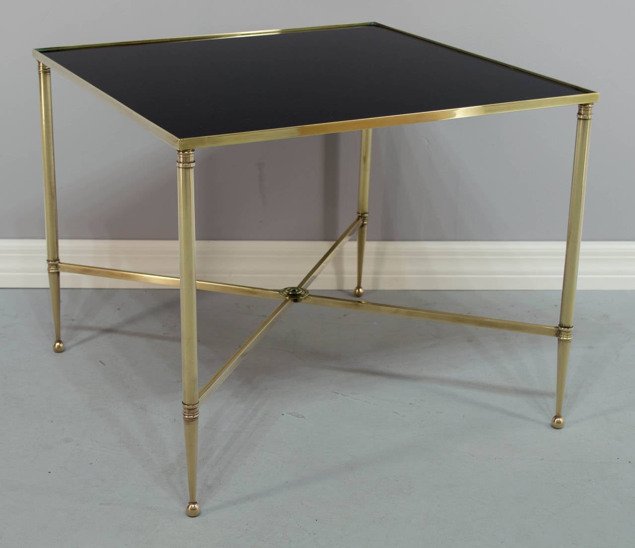 Small French square cocktail or side table made of solid brass with black glass top. Attributed to Maison Jansen. Brass has been polished but not lacquered. More photos available upon request. We have a large selection of French antiques. Please