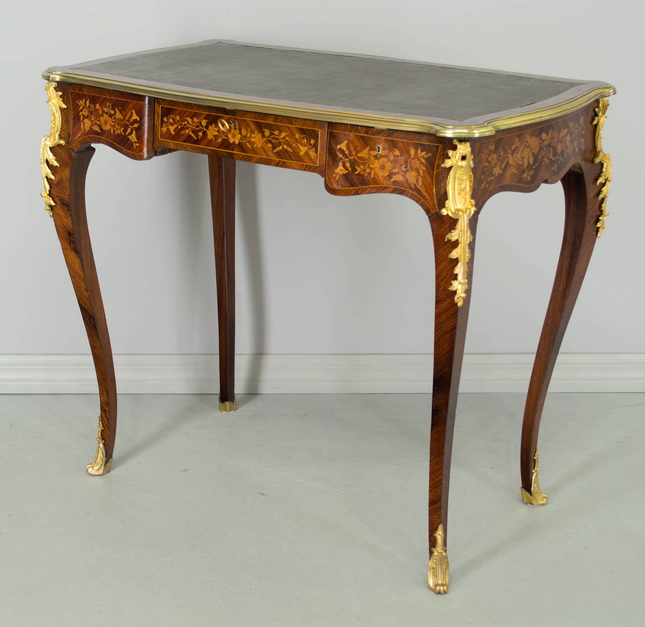 19th century Louis XV style marquetry, gilt bronze mounted ladies desk with three dovetailed drawers. Finished on all four sides with fine floral motif inlay of rosewood and tulipwood on solid mahogany. Elegant slender curved legs with bronze