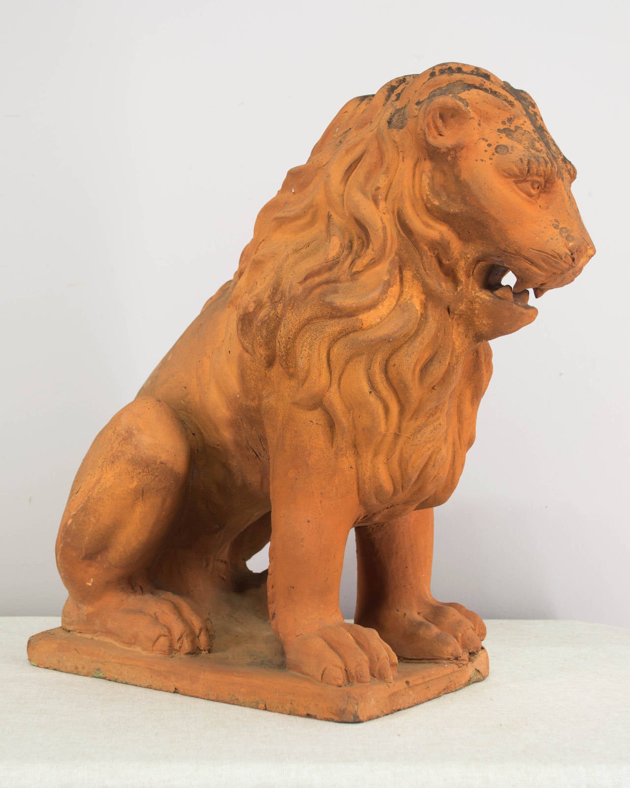 19th century French terracotta lion, with nicely detailed mane and old mossy patina. A stately sculpture to grace your front entry or garden. In good condition with no restoration. As always, more photos available upon request. We have a large