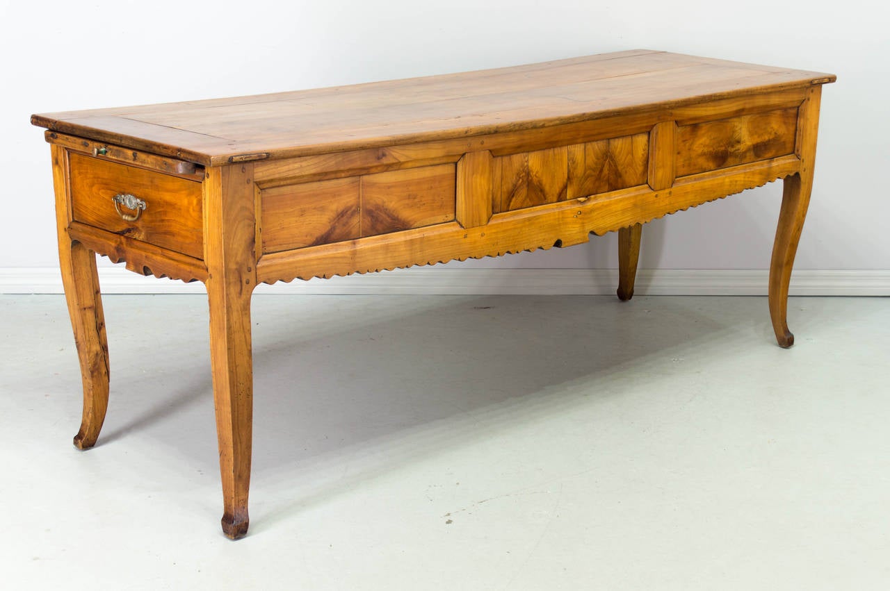 19th century Louis XV style table de gibier from Normandy made of solid cherry with chestnut as a secondary wood. This was a hunt table for wild game and has deep drawers on either side and a pull out cutting board. Nicely detailed apron with book