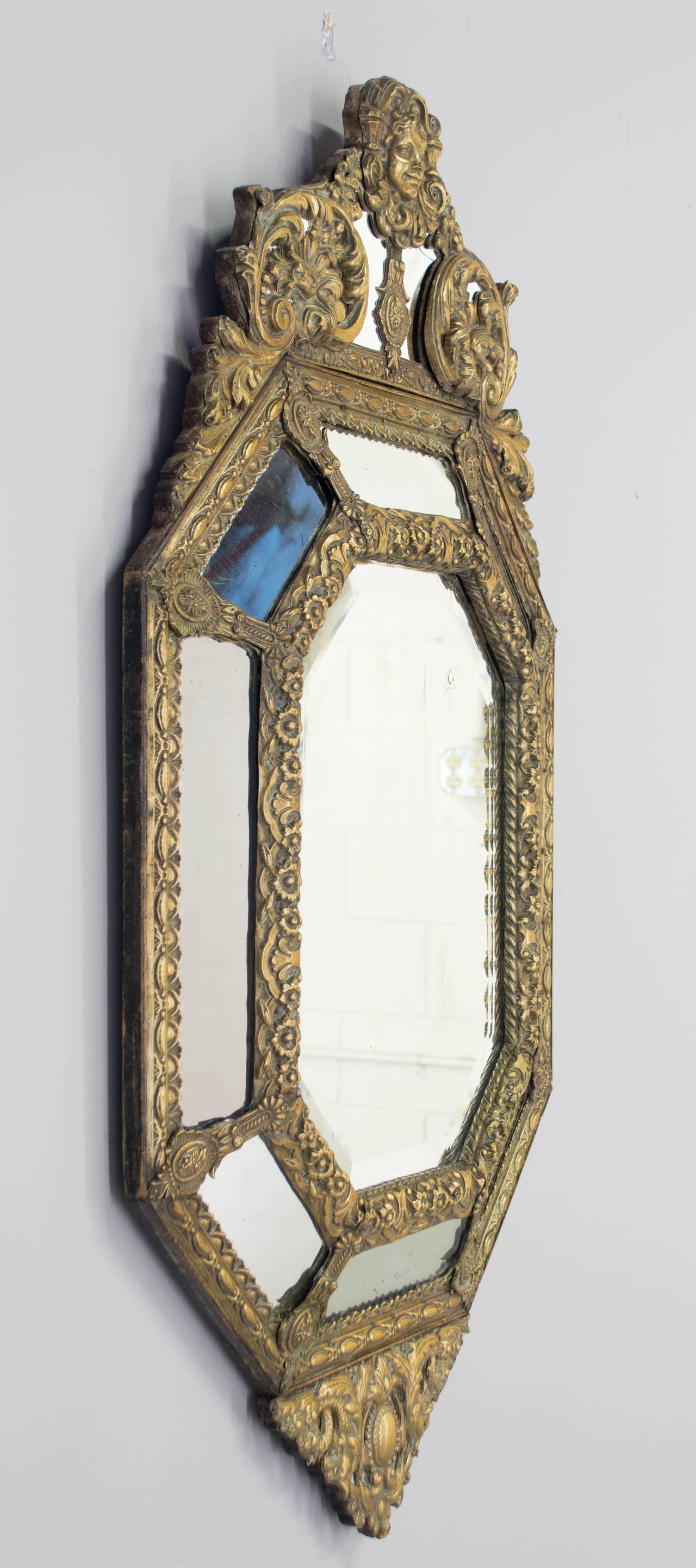 19th century French Renaissance style mirror with intricately embossed brass frame. Elongated octagonal shape with triangular pediment. Center mirror has 1-1/2" bevel.
Condition : Good overall with two minor break on the top. See Picture # 5 &