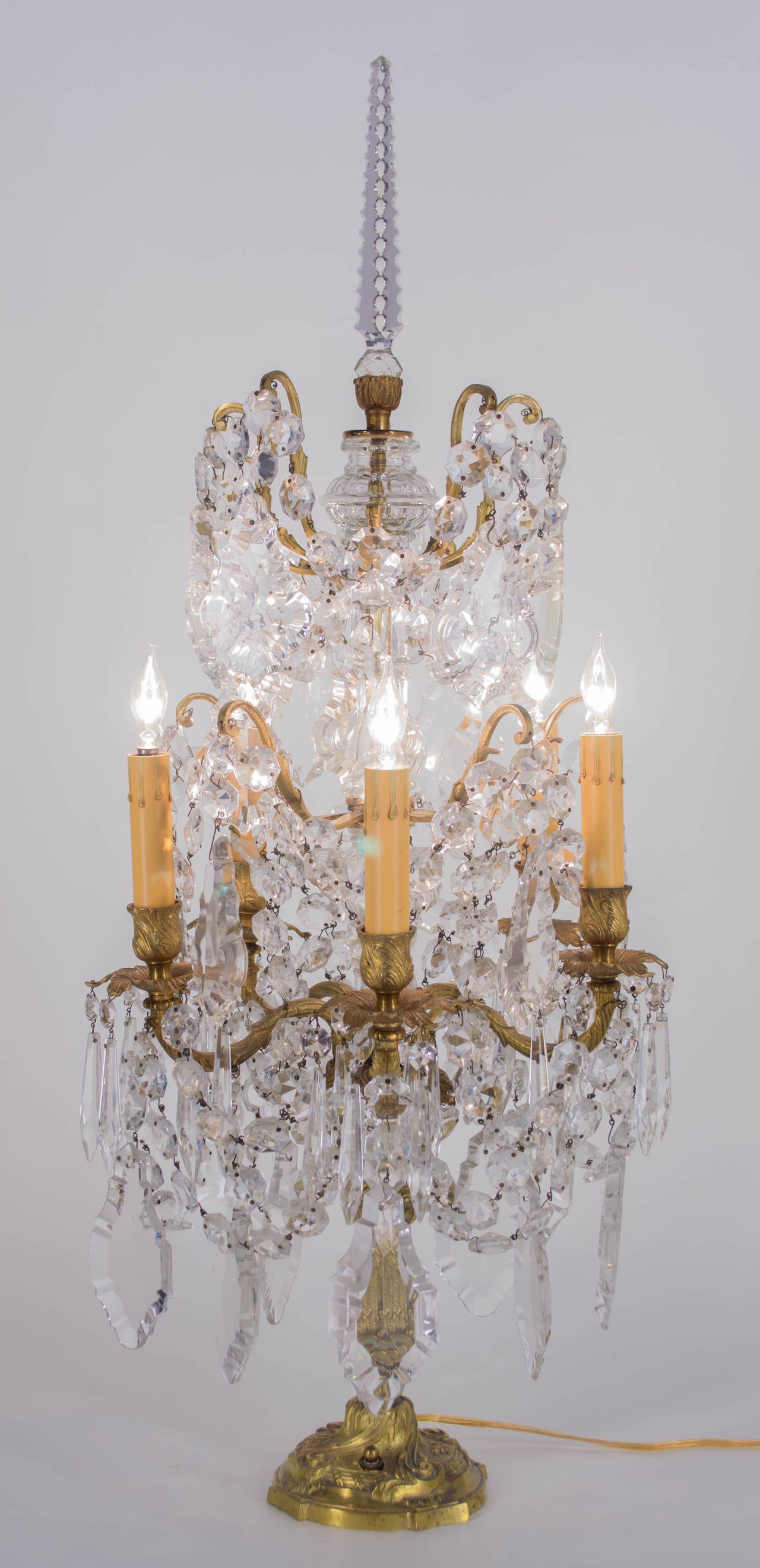 An early 20th century French bronze six-light girandole dripping with crystal prisms including dangling pendalogues, swags of jewel chains between each arm, ribbed glass columns and a cut crystal spire. Rewired. 
More photos available upon request.