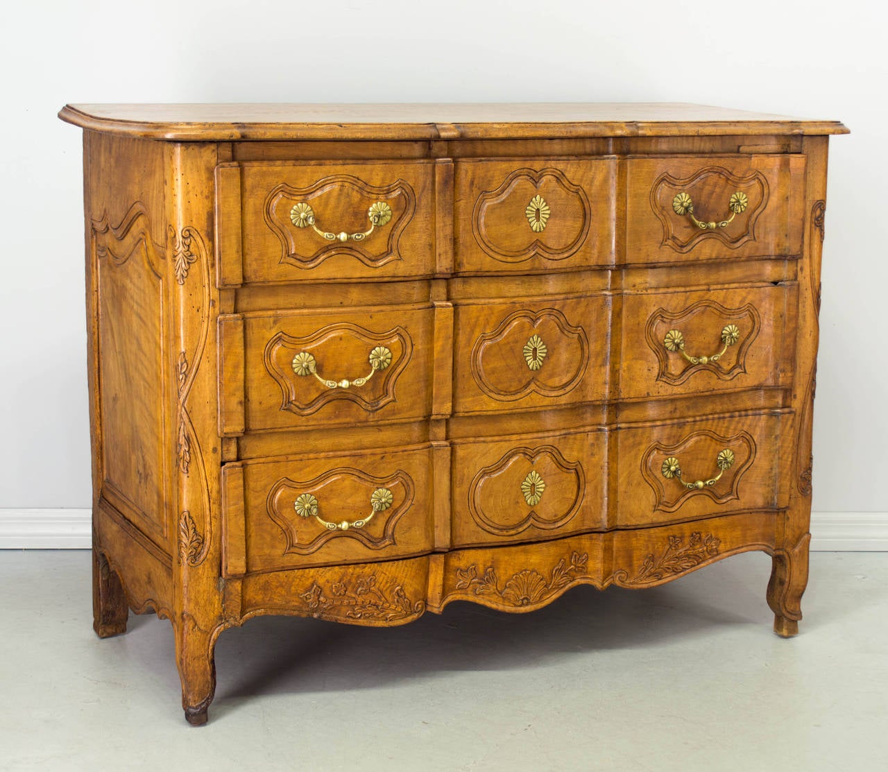 18th century French Louis XV style commode with an arbalete front, or crossbow front made of blond walnut with nice honey color. Top is made from a single plank of wood. Carved details on the apron and front curved corners. Three dovetailed drawers