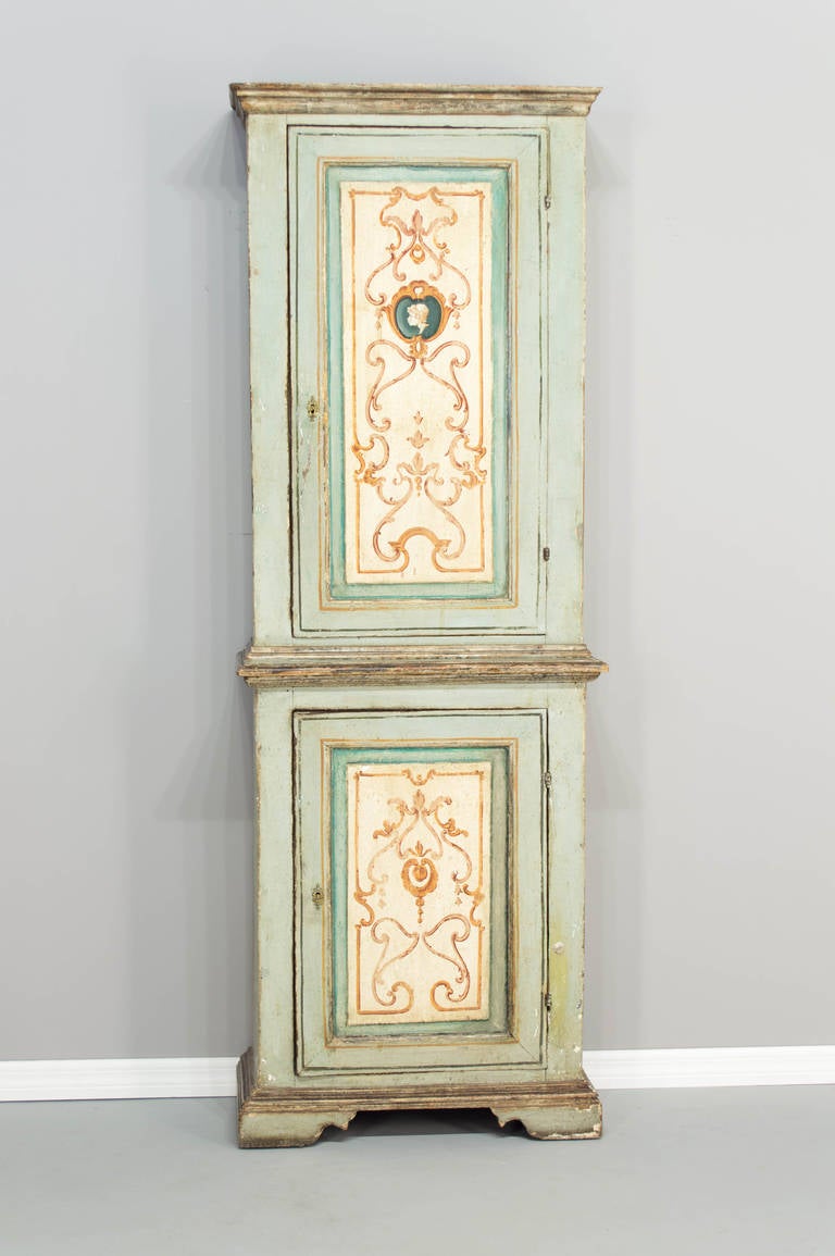 An Italian painted cabinet with a door above a door opening to reveal the interior with fabric and glass shelves. Two original locks in working condition. The painted decoration was probably done in the late 19th century. A nice decorative