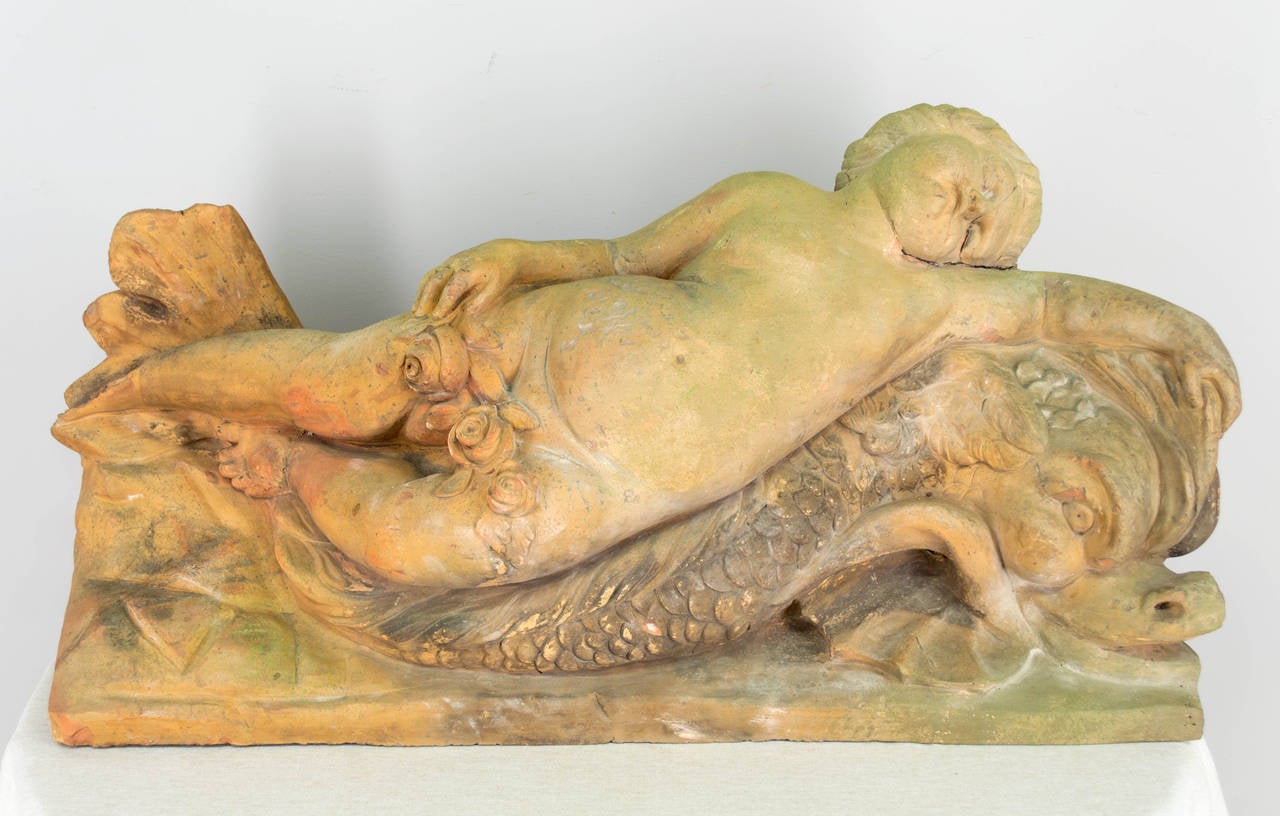 Late 19th century French terra cotta garden sculpture of a sleeping cherub atop a dolphin. More photos available upon request.