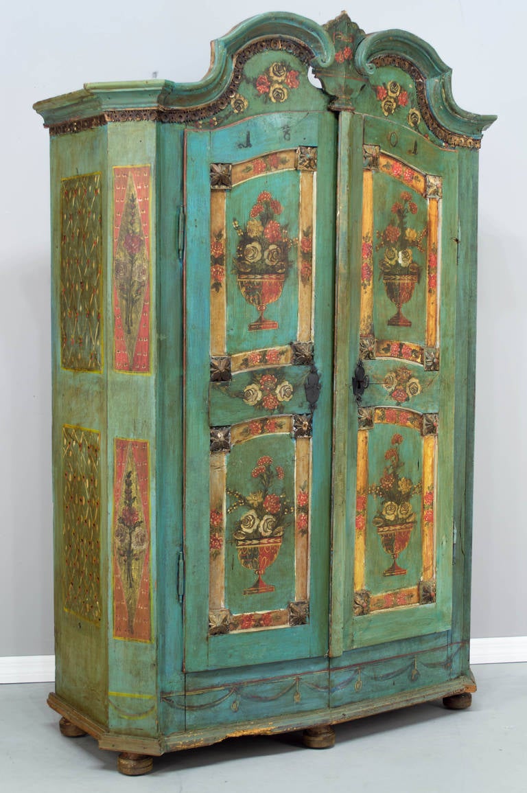 A superb polychrome painted armoire from the Alsace Province, made of yellow pine and retaining its original floral paintings with a double arch crown. Interior has two shelves on the left and and an open space on the right with wooden hooks for