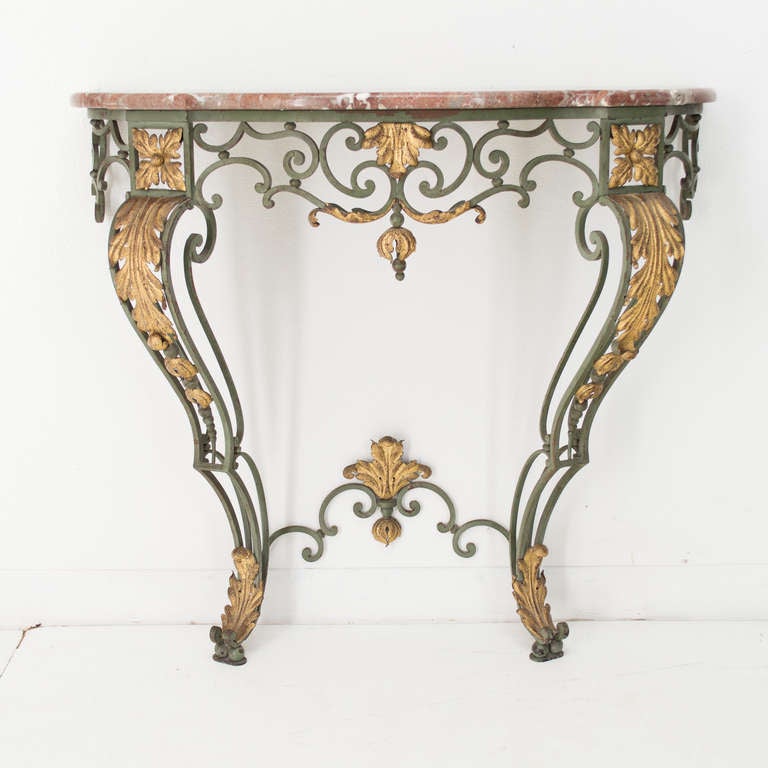 A vert de gris and gilded wrought iron console with a rouge marble top. Serpentine front and double framed legs.