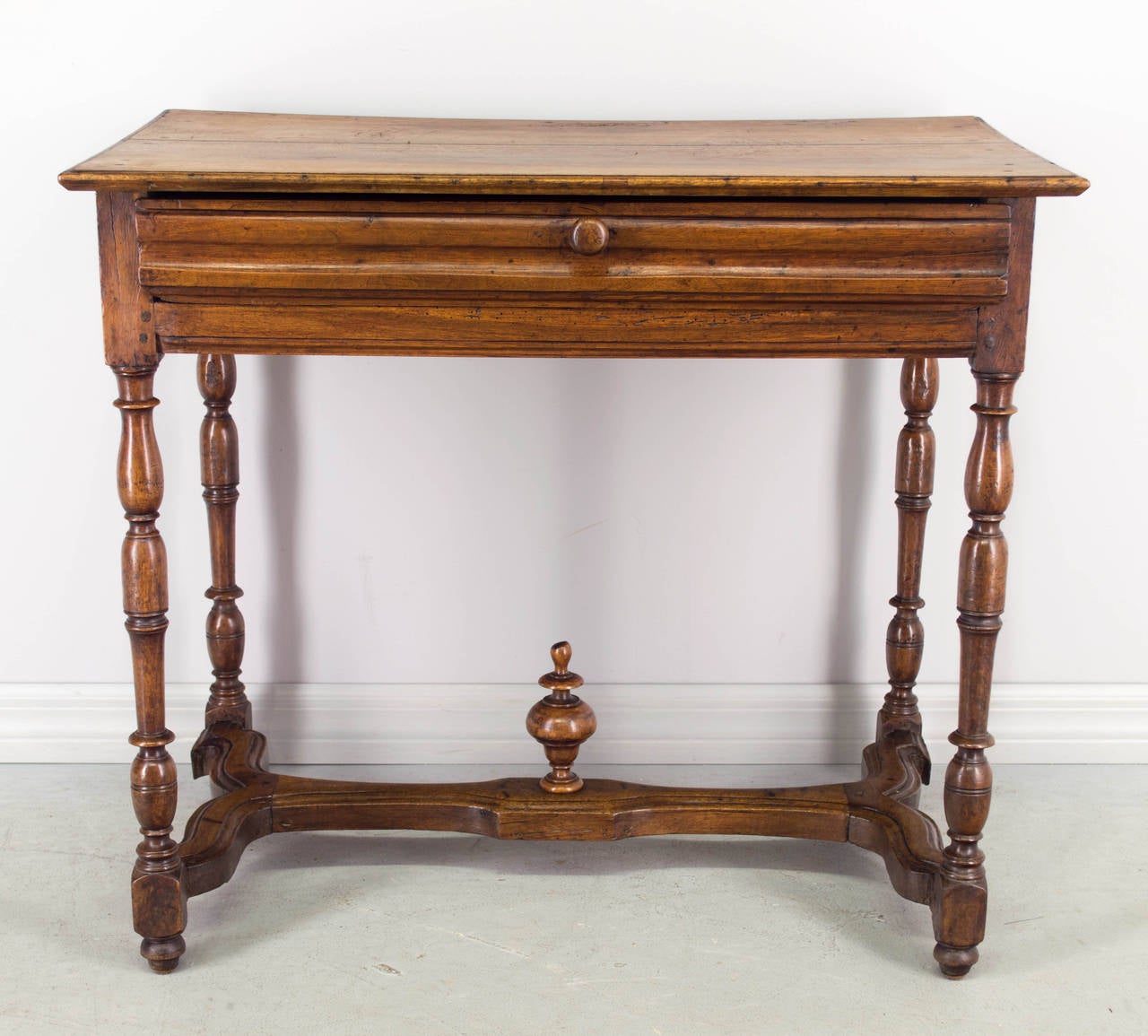 Early 19th century Louis XIII style French side table, made of solid walnut with large dovetailed drawer. Fine turned legs and shaped stretcher with finial. Top is made from two planks. Pegged construction. Waxed patina. Nice proportions for use as