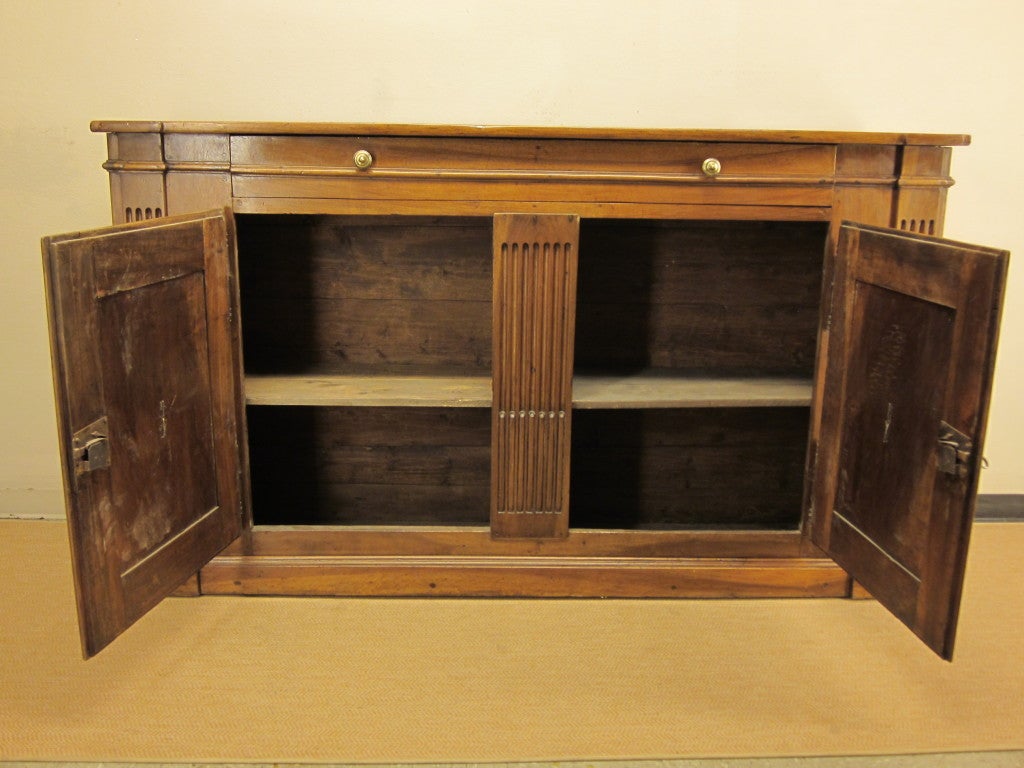 A grand buffet made of walnut having a large dovetailed drawer above two doors. Retaining its original brass hardware and locks. Top constructed of two walnut planks.Lovely warm patina. 20' depth at the top.
For many more fine antiques, please