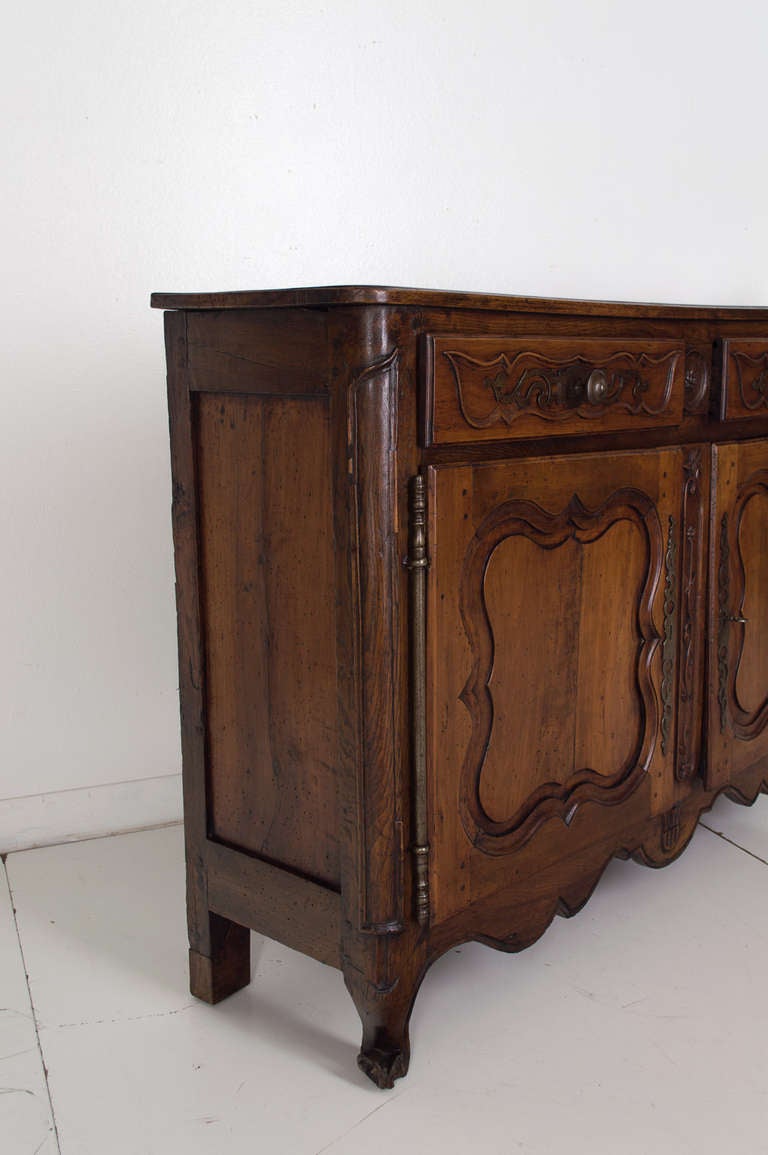 A Louis XV Fruitwood buffet with two raised panels doors below two dovetailed drawers with its original hardware from the Loire Valley. Typical construction from a local country cabinet maker, using different woods, walnut for the top, pear wood