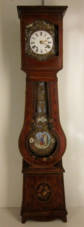 A very attractive seven day Morbier clock in a painted pine case from the east of France. Chimes on the hour and two minutes after and on the half. The sound is a gong. Brass embossed pendulum and face with polychrome paint. The pendulum represent a