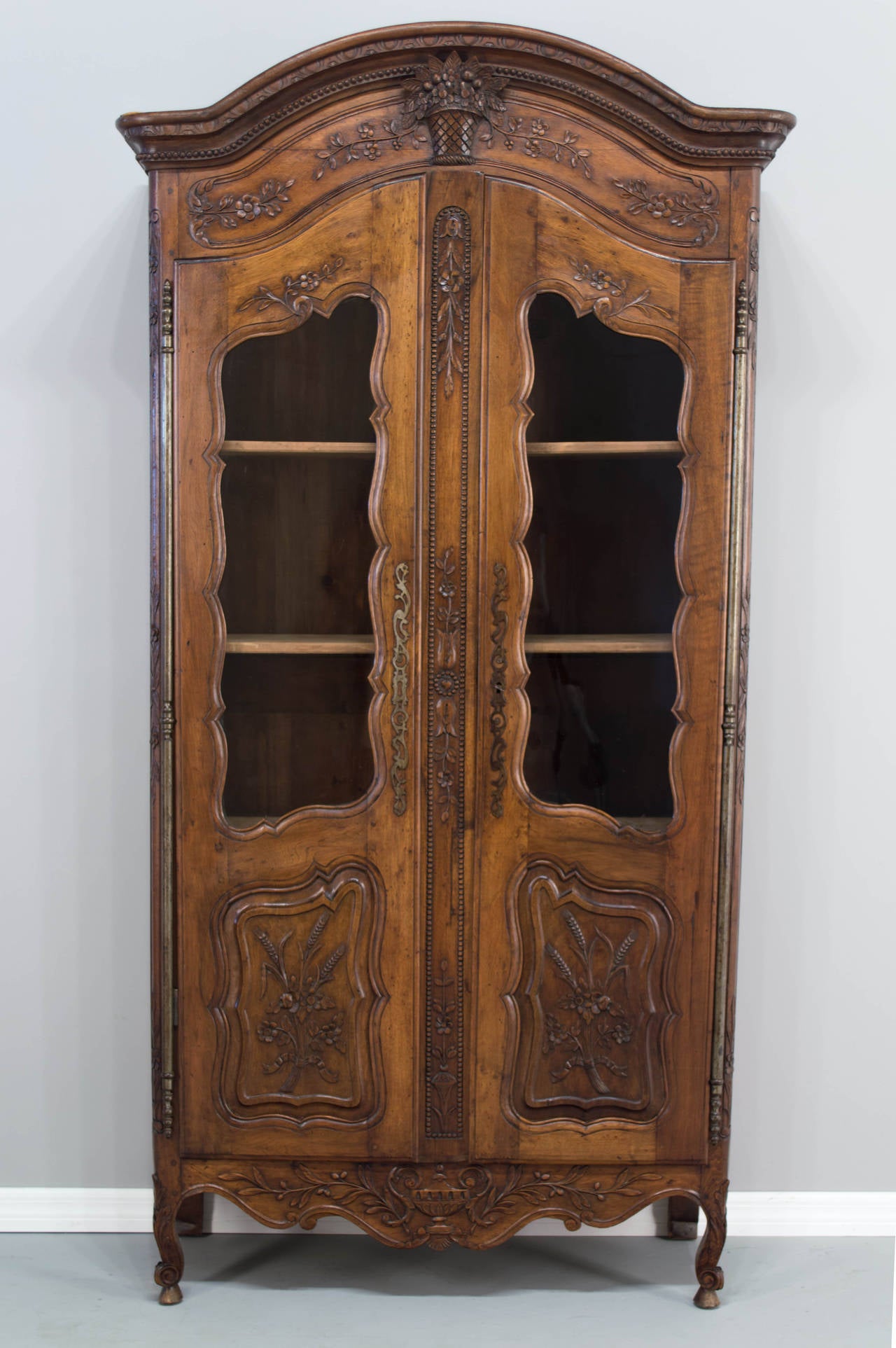 This vitrine was made in the first part of the 20th century by an artisan as it is all pegged construction and hand-carved, a beautiful walnut from Provence, a Chapeau de Gendarme crown, adjustable shelves, original glass doors re-glazed. A great