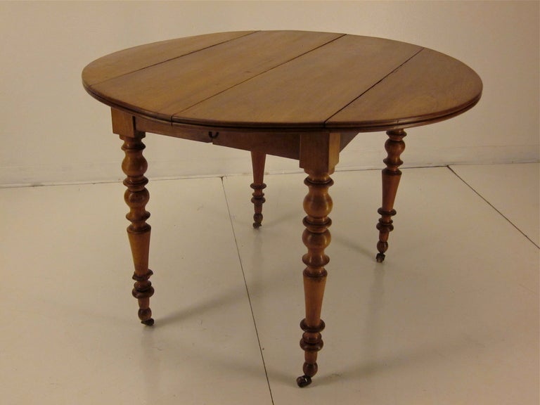 A Louis Philippe table made of cherry wood from the Normandy province with four turned legs on brass cast wheels. Could be used as a side table or dining table. New runner for the extensions but no leaves for the table ( could extend to 79