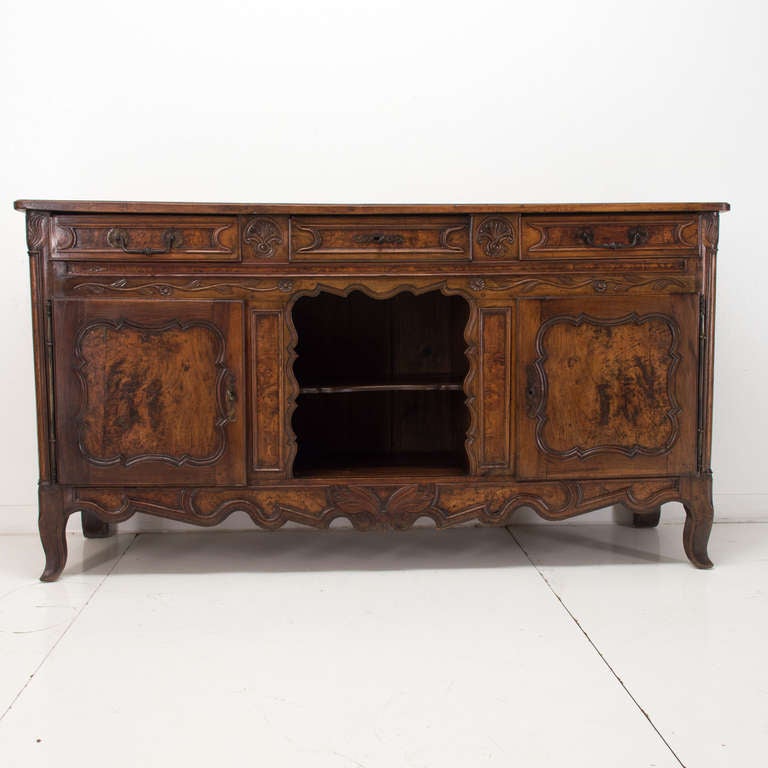 An enfilade from the Burgundy Province made of walnut and burl of oak with three dovetailed drawers and two doors with some fine carvings. A good sideboard with plenty storage and with the middle niche for display. Beautiful warm waxed finish.