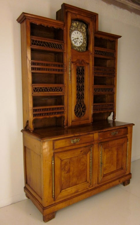 A grand vaisselier made of cherry wood and chestnut from the Brittany province with a Morbier clock and elaborate pierced details and brass nails and hardware. The height of the buffet is 39