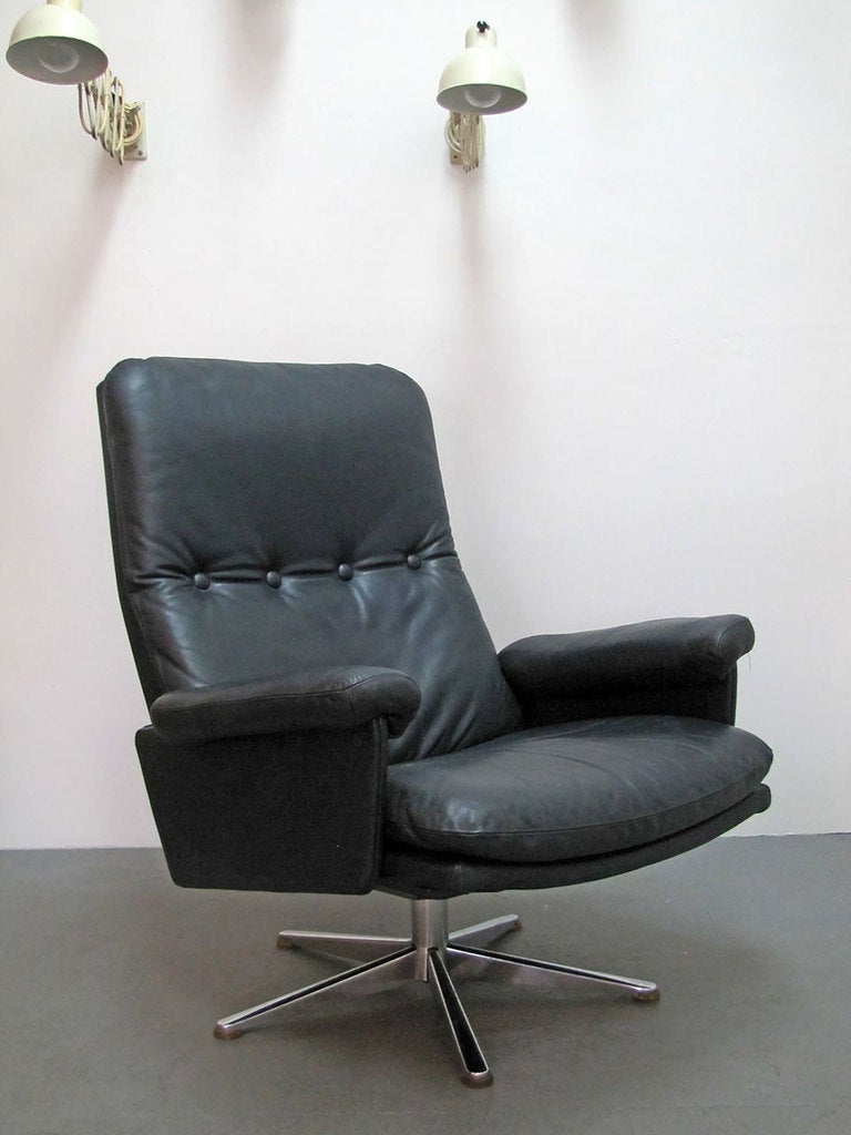 pair of large De Sede leather lounge chairs.
original thick, dark blue leather with button details,
rotating swivel base
