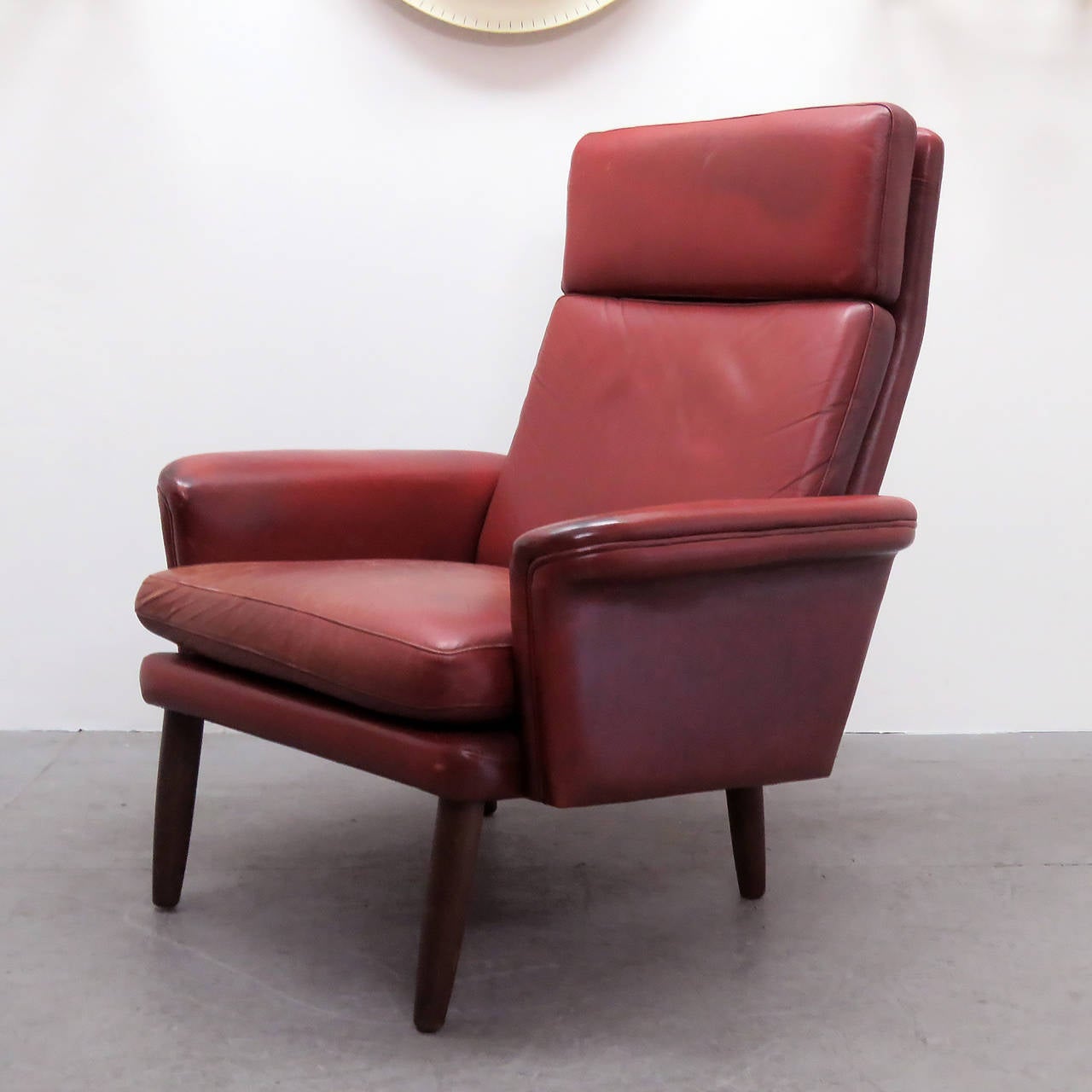 Great Danish high back leather lounge chair in well-aged red leather with loose down cushions and teak legs.