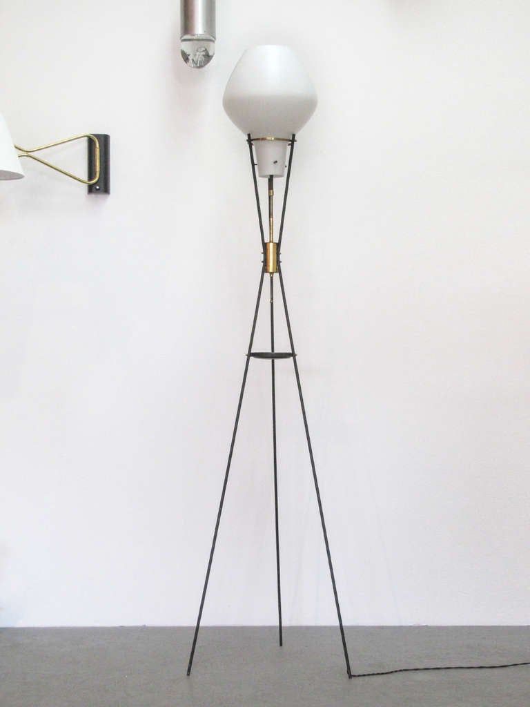 stunning Italian floor lamp attributed to Stilnovo. The elegant tripod base features three distinct connection elements including a small dish and a pull chain on/off switch and hold a large satin white cased glass body