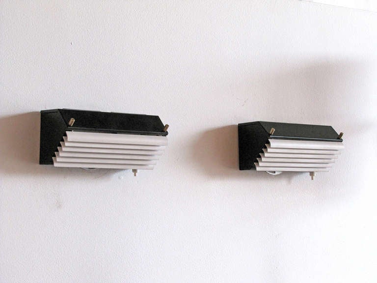 black enameled french metal sconces by Jacques Biny, white enameled louver front, brass accents and individual on/off switch on each fixture, priced as a pair