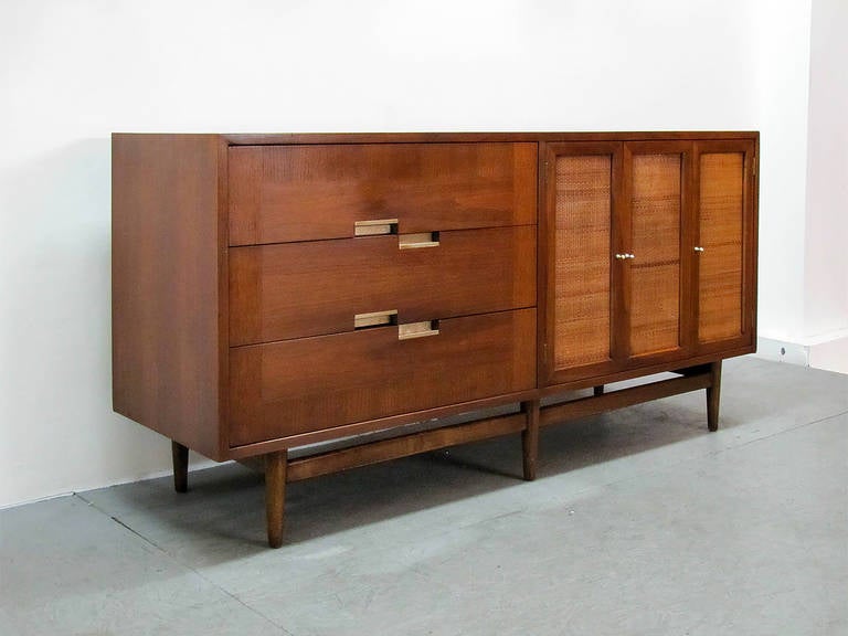 Wonderful walnut sideboard by American of Martinsville in great original condition, featuring three dovetailed drawers with brushed aluminum insert handles and three canned doors, revealing two center shelves and three additional drawers to the