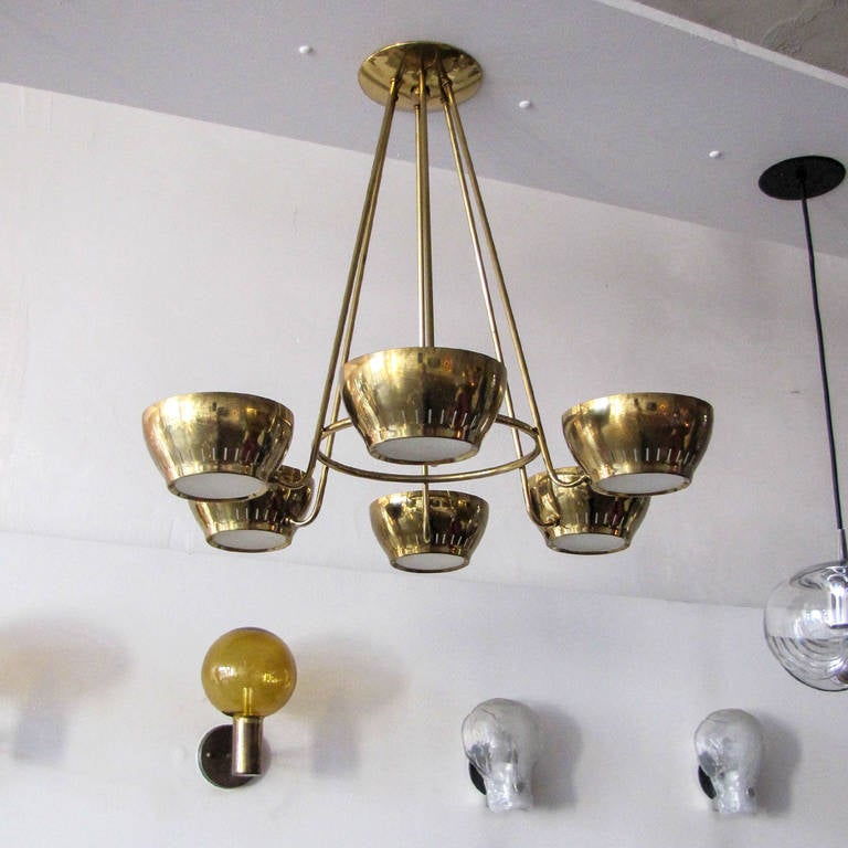 stunning six arm brass chandelier by Gerald Thurston for Lightolier, each arm holds a brass cup with ring perforations and a textured glass inlay on the bottom, marked