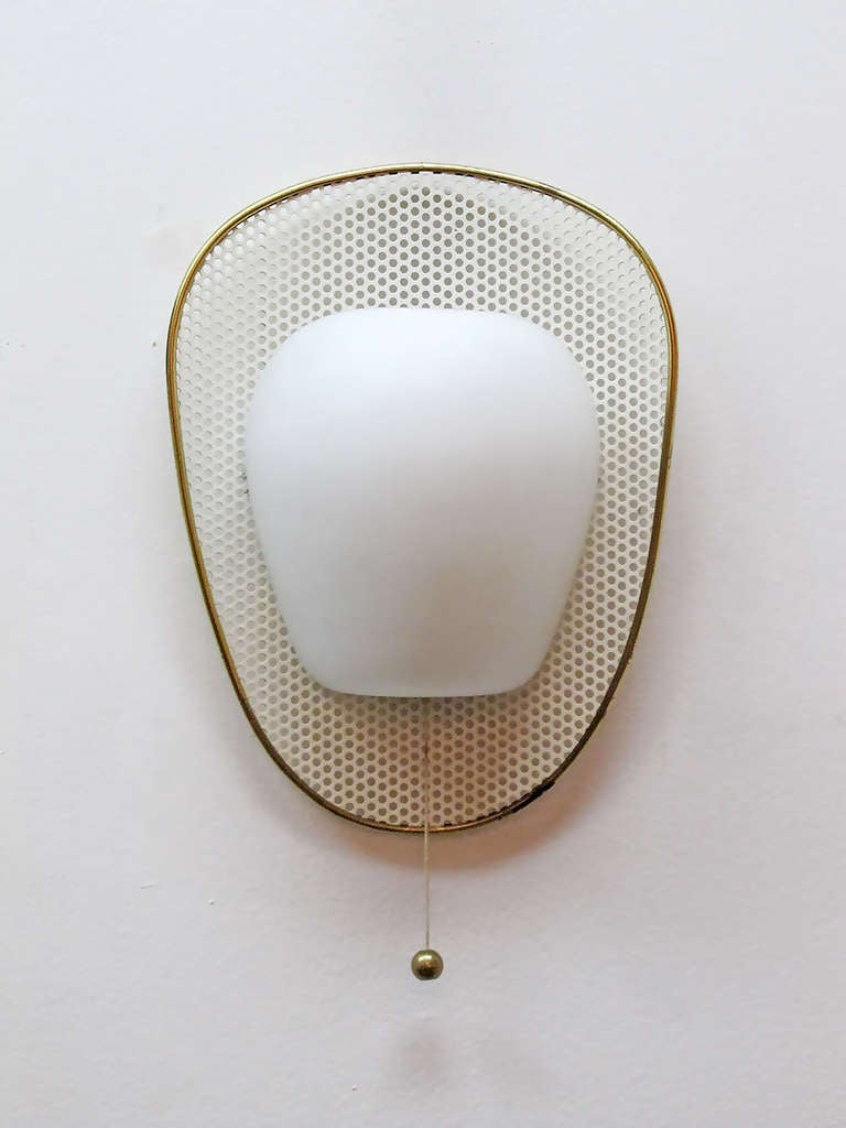 set of three elegant French wall lights attributed to Mathieu Matégot, opal glass shell on a perforated, enameled metal shield with brass rim, individual brass ball on/off switch