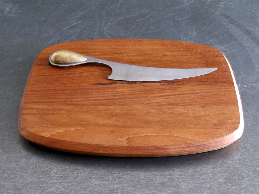 teak cheese board and sculptural stainless steel knife with brass handle by Dansk International Designs Ltd Torun Japan, knife handle fits into an indentation on the board