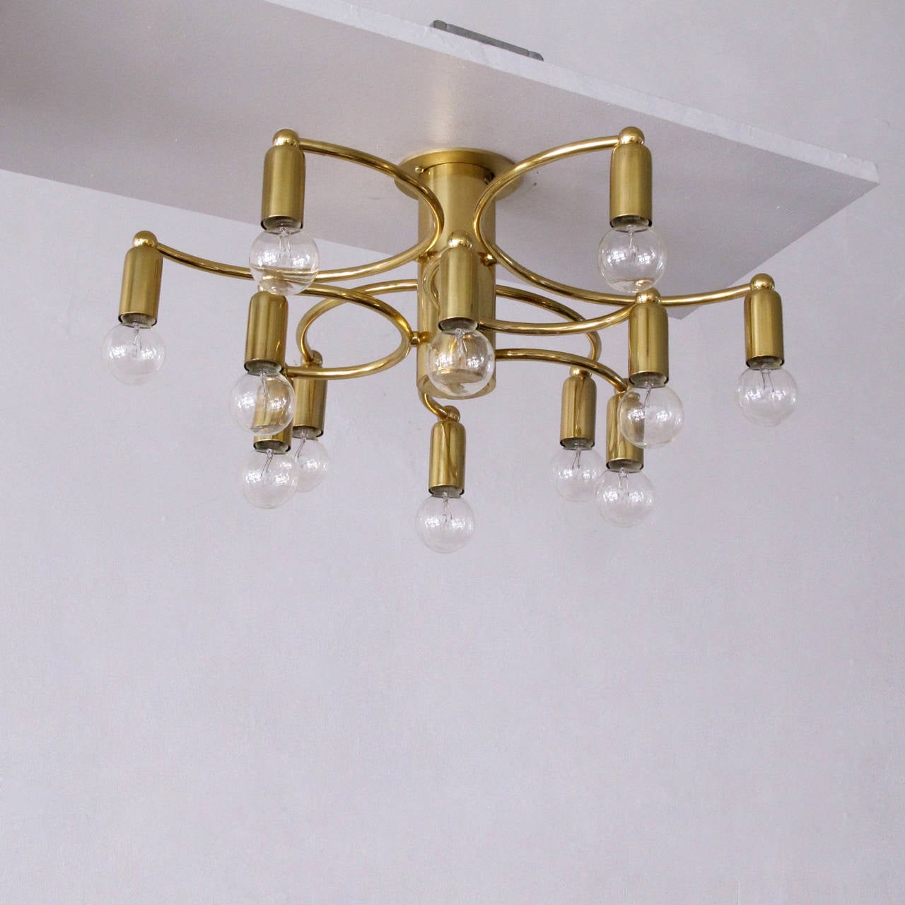 Wonderful brass twelve-light flush mount ceiling light by Gaetano Sciolari with two tiers of three semi-circular arms, each equipped with two sockets on either end, can be used as wall sconce as well.