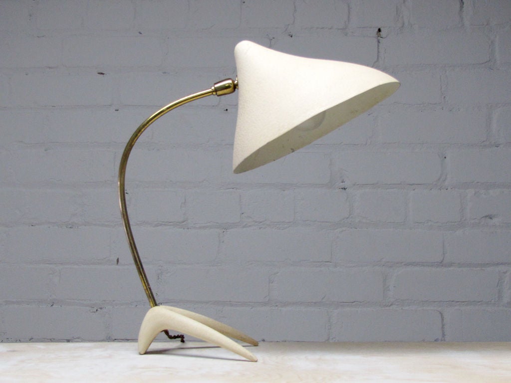 elegant cream table lamp designed by Louis Kalff for Philips<br />
the conical shade is held by a curved brass stem on <br />
an organically shaped base, resembling a crow's foot.