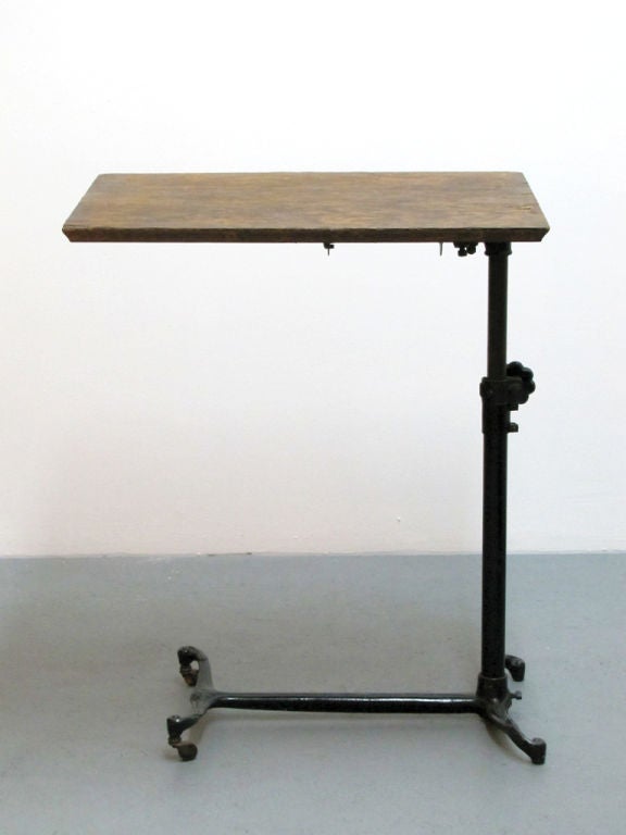 tilt top drafting / serving table produced by Sidway Elkhart circa 1900 <br />
the ornamented cast iron base features two wooden rolls and two fixed feet <br />
the adjustable height ranges from 22.5