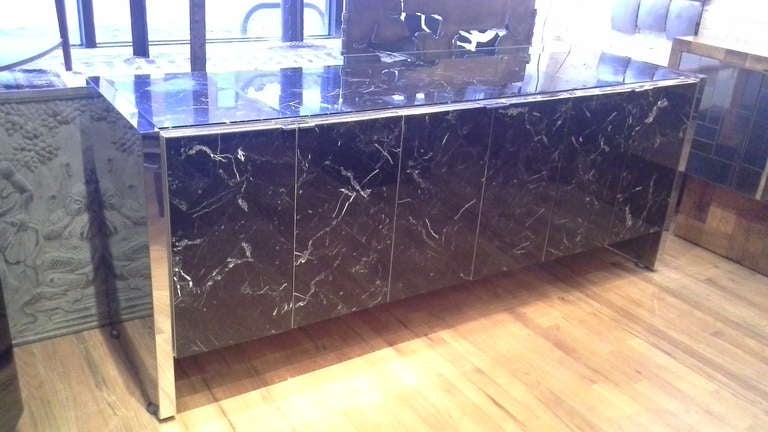 A stunning six door Ello credenza executed in a herringbone patterned tessolated black marble.The credenza is accented with chrome trim and side panels. Inside is white lacquered storage with adjustable shelves. One of the finest finish options