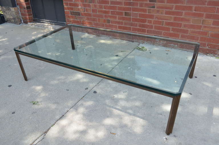 Bronze and glass large coffee table with fluted legs. The glass top is thick.
