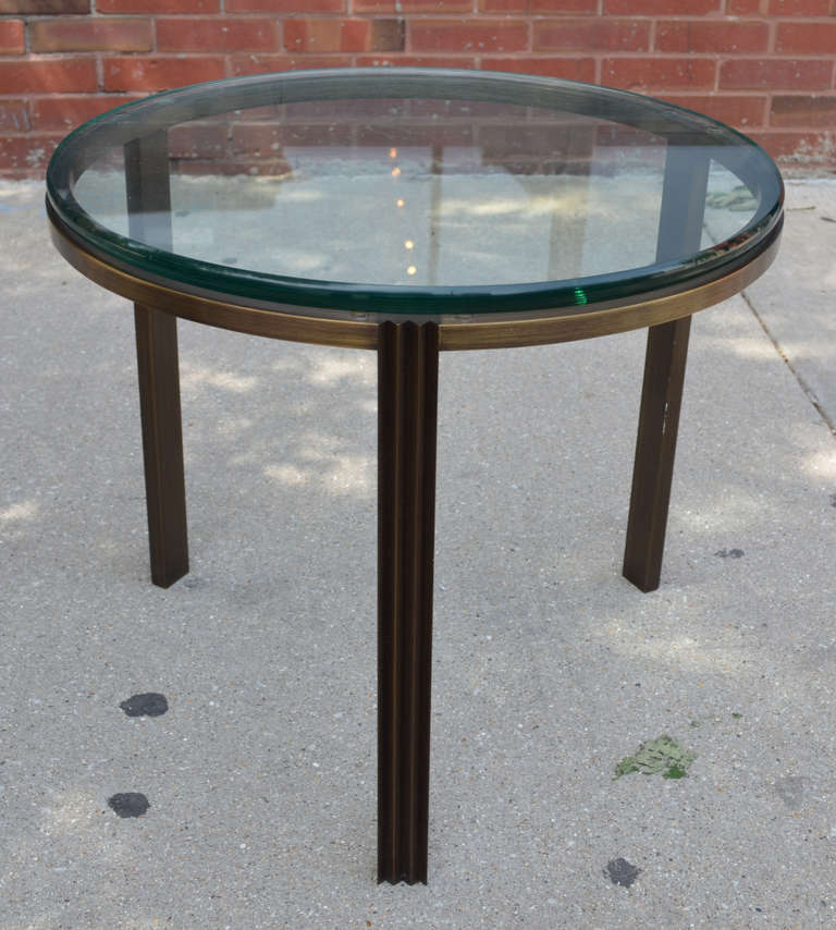 An elegant bronze end table with an exceptionally thick round glass top. The legs are fluted.
      
    