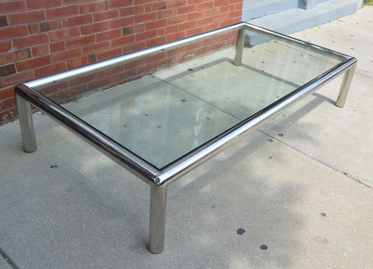 A exceptionally large thick chrome tubular coffee table with glass top.

The table is over 6 feet long.

The glass has a small chip on the side and a larger chip to the corner.