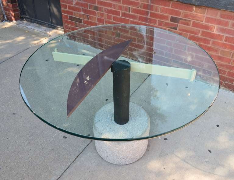 An Italian round glass dining table in the style of Peter Shire. The base is constructed with powder coated steel tubes and is anchored with a concrete base. Would make a wonderful side, center, or dining table.

