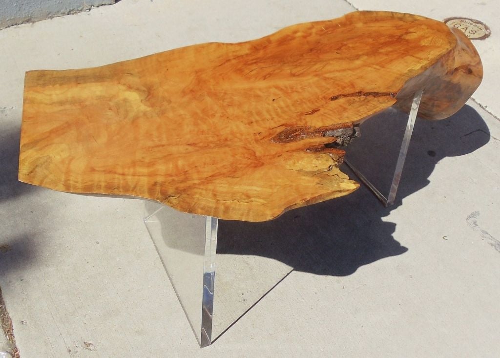 A free edge wood coffee table with  lucite legs.