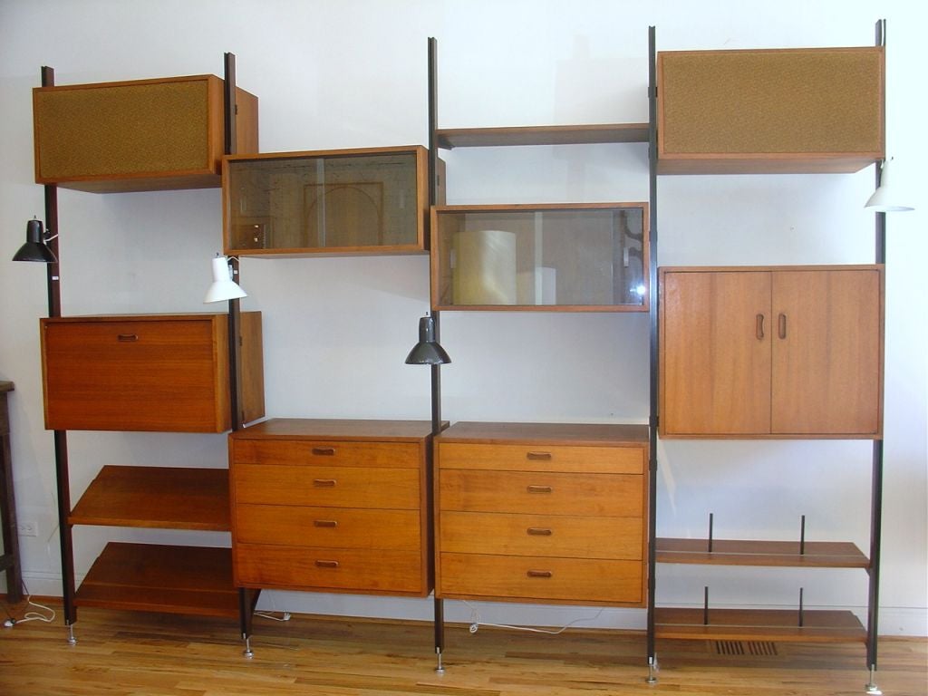 This George Nelson Omni Wall Unit features five uprights, two cabinets with drawers,two cabinets with sliding glass doors,two open cabinets, one cabinet with a drop front desk, three shelves with book divider channels, two slanted presentation book