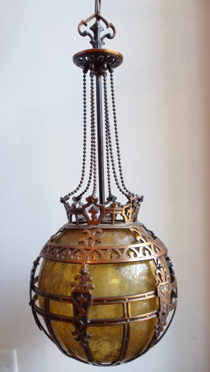 A hand wrought Neo-Renaissance metal and glass hanging pendant ceiling light.